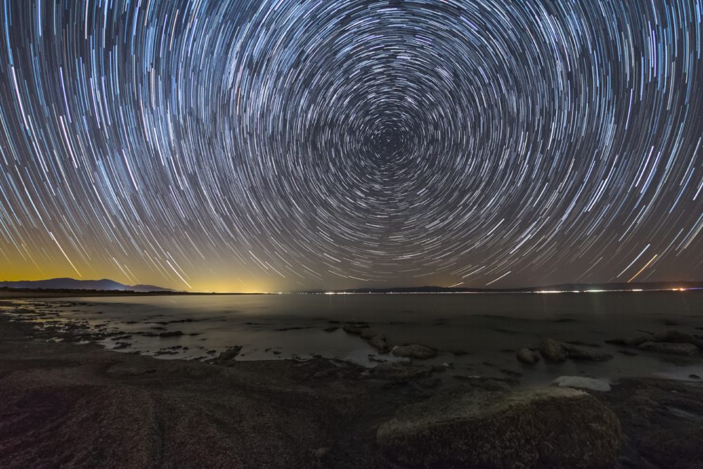 In a long-exposure shot, the stars make circling, concentric trails in the night sky.